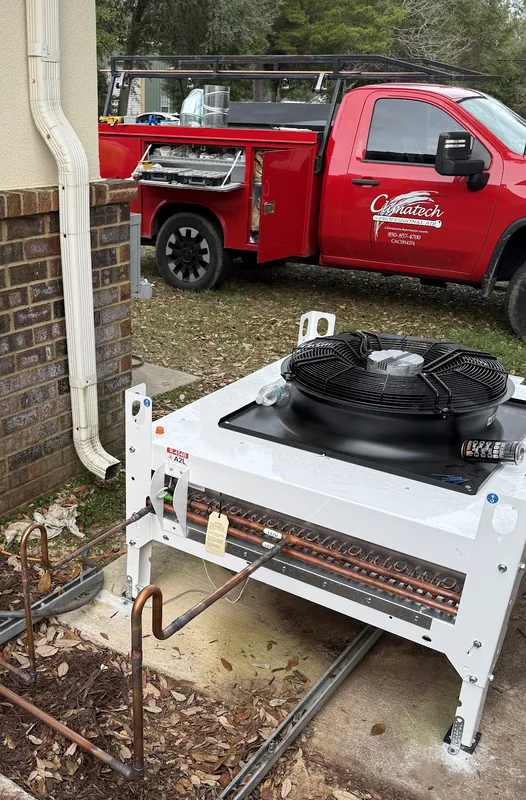 Newly installed Climatech outdoor condensing unit beside a Pensacola home, with a branded Climatech service truck parked behind