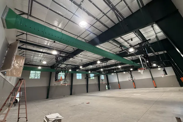 Green fabric duct running the length of a steel-framed gym