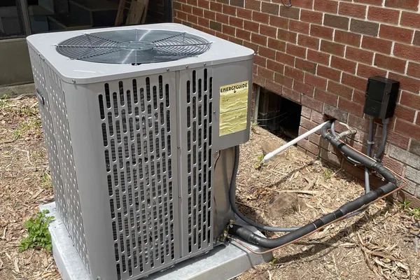 A residential condensing unit beside a brick home
