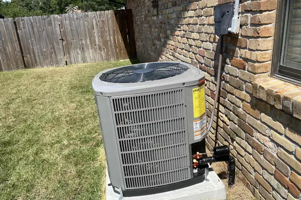 A residential condensing unit installed on a lawn-side pad