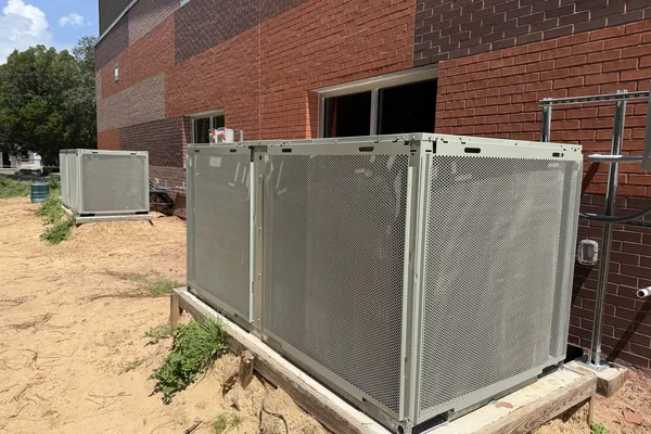 Commercial rooftop units set beside a brick building