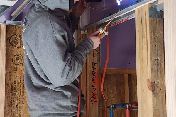 A Climatech technician running ductwork during a build-out