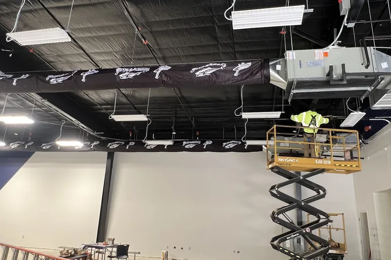 Commercial HVAC work by Climatech of Professional Air &mdash; fabric duct being installed from a scissor lift during a build-out