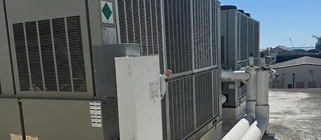 Commercial rooftop chiller units with insulated piping on a flat roof