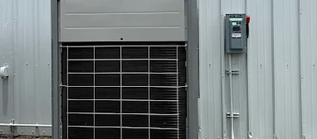 Heat pump condenser unit and electrical disconnect mounted against a metal building wall