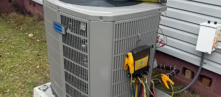 Refrigerant manifold gauges connected to a residential air conditioner during a maintenance visit